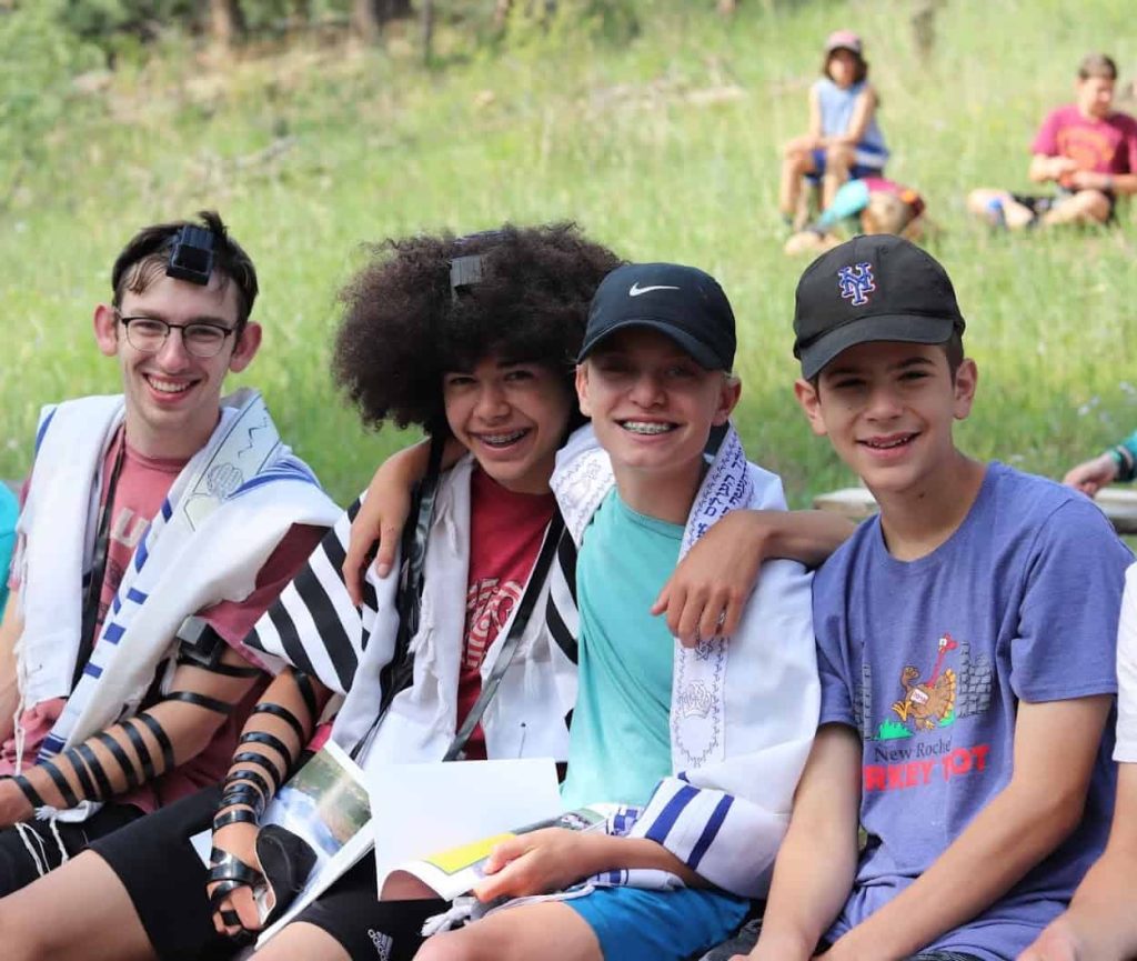 three bogrim boys with counselor embracing while at morning shacharit services