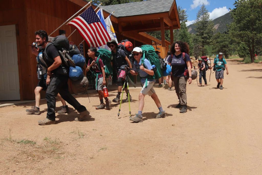 Image of teen campers returning to camp property from a backpacking trip.